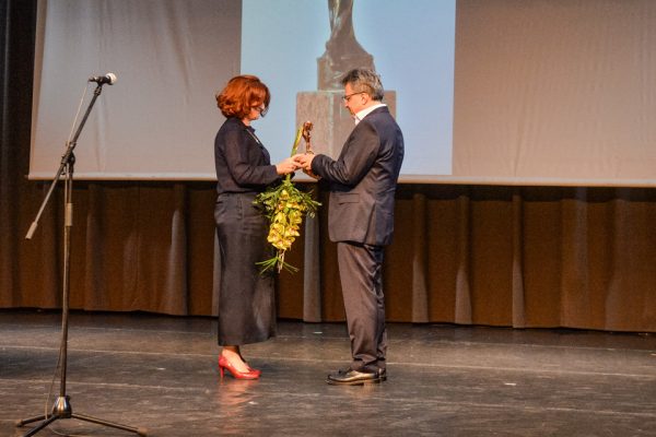 Dr. Assani Omar átveszi az Elfogadás -díjat Maka Piroskától, a művelődési ház színpadán