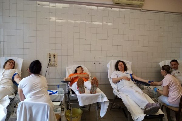 A képen négy önkéntes véradó fekszik a speciális ágyakon és a kórház asszisztensei felügyelik a véradásukat.