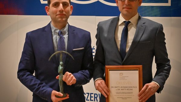A képen látható: bal oldalon Dr. Watti Rézan, kezében a Príma díj, jobb oldalon Dr. Watti Jezdancher PhD., kezében oklevél, melynek olvasható felirata: P Vármegyei Prima OKLEVÉL Dr. Watti Jezdancher PhD. Dr. Watti Rézan, a VOSZ Vármegyei elnökségének szavazata alapján Önök nyerték el a Magyar Oktatás és Köznevelés kategóriában a Heves Vármegyei Prima díjat, valamint két aláírás